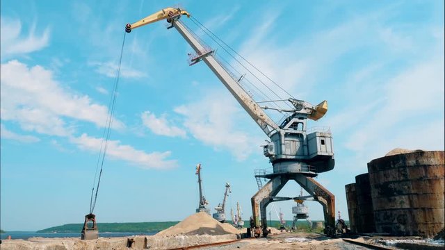 Big crane moves crushed stones, stocking them in a pile.