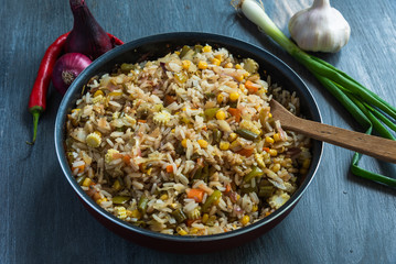 Vegetarian fried rice with cabbage, carrots, corn, onions, beans and peppers in a pan close-up - a popular dish of Indian and Asian cuisine