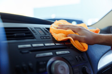 Image of male's hand with orange rag washing car interior