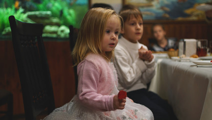 Cute serious little girl sitting at the table with her friend