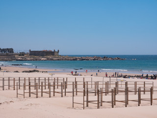 Beach in Matosinhos, Porto, Portugal with beach hut frames in foreground and Cheese Castle fort in background