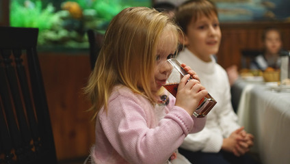 Cute serious little girl sitting at the table with her friend