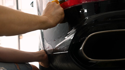 Close up to PPF installation process on a front (rear) headlight and bamper. PPF is a Paint Protection Film which protect paint from scratches and stone chips. Concept of: Film, Car, Service, Slow Mo