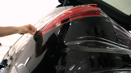 Close up to PPF installation process on a front (rear) headlight and bamper. PPF is a Paint Protection Film which protect paint from scratches and stone chips. Concept of: Film, Car, Service, Slow Mo