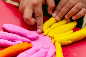 Fototapeta premium improving fine motor skills educational games concept, modeling soft clay plasticine children's hands close-up red background