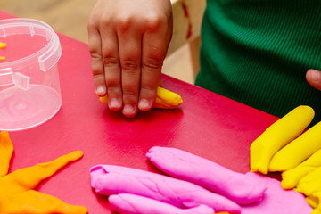 improving fine motor skills educational games concept, modeling soft clay plasticine children's hands close-up red background