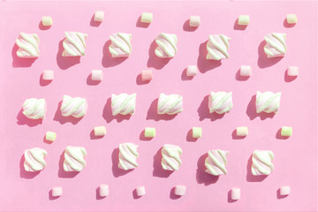 Sweet beze, white marshmallows on pink background. Pastel color dessert. Top view, flat lay.
