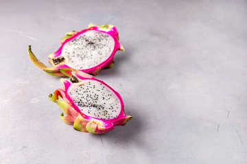 Obraz na płótnie Canvas Fresh Organic Pitahaya Dragon Fruit Cut in Halves on Gray Background Tasty Tropical Fruit Copy Space