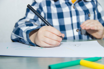 The boy draws felt-tip pens on paper. Drawing. Little boy. Children's drawing. Developmental activities.