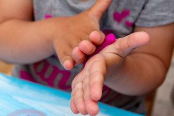 improving fine motor skills educational games concept, modeling soft clay plasticine children's hands close-up blue background - obrazy, fototapety, plakaty