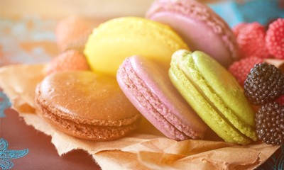 Delicious colorful macaroons with berries on parchment paper