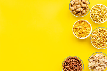 cereals, oatflakes and cornflakes for healthy breakfast on yellow background top view mock up