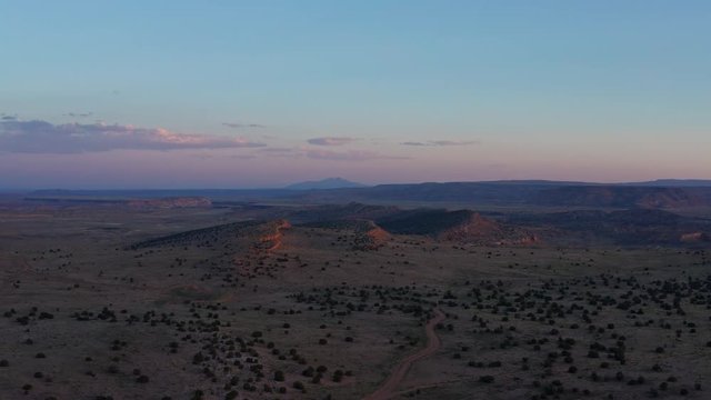Aerial drone fly away backwards shot evening shot of the twilight over the canyons and the mountainous rock formations in the vast wilderness of the New Mexico Desert, Albuquerque, Southwest, USA