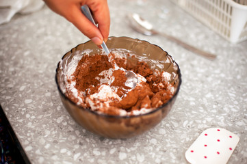 Woman hand with spoon mixes cream with cocoa and coconut cream.