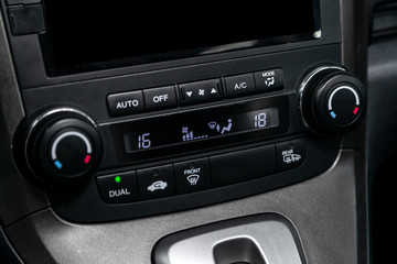 Сlose-up of the car  black interior:  dashboard with temperature, clock, adjustment of the blower, air conditioner and other buttons.