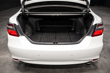 Close up Rear view of a  sedan white car with open trunk in garage. Empty car trunk