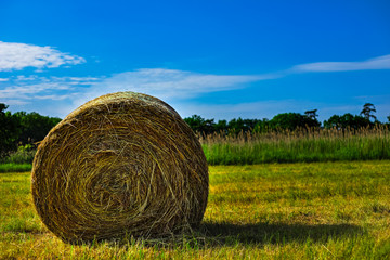 HDR Photo of Sraw Bales on the field with clouds and blue sky.
