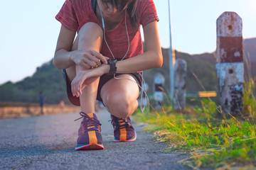 legs of woman kneel down to takes reset start time of running on watch on hand, period of time...