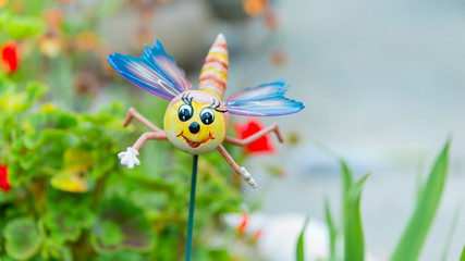 A novelty garden ornament positioned on a stem in a flower bed within a domestic garden