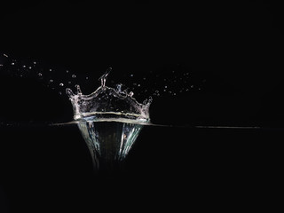 Splash of water isolated on black background, close up view. Drop of water makes splash on surface, background for overlays design, screen blending mode layer