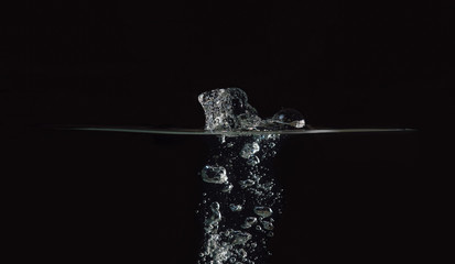 Water surface with bubbles isolated on black background. Drop of water fallen into liquid. Black...