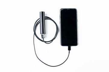 Black mobile phone and charger isolated on white background.Copy space