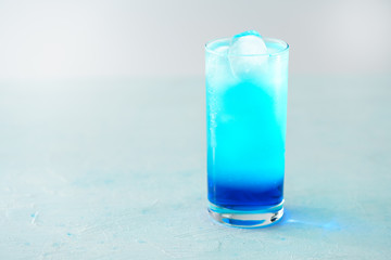 Blue Lagoon cocktail is a collins glass. Light blue background, real ice, high resolution