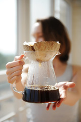 Girl barista holds an unusual creative coconut shell pourover drip alternative coffee brewing