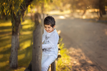 A child is sitting on a wooden fence. Spring time