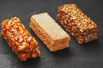 Healthy snacks. Fitness diet food. Grain bar with peanuts, sesame and seeds on a cutting board on a dark table, energy bars
