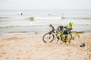 Fototapeta premium Two bicycles stand on beach against sea