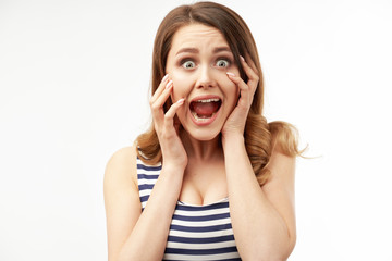 Portrait of impressed female with stunned expression, keeps hand on opened mouth, emotional irritated cute woman screams loudly, expresses negative emotions, isolated on white background