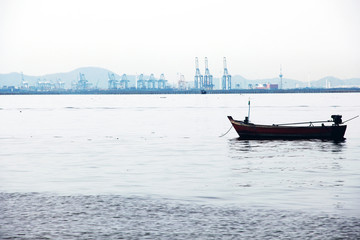 Fishing boat in ocean and building in the city background.