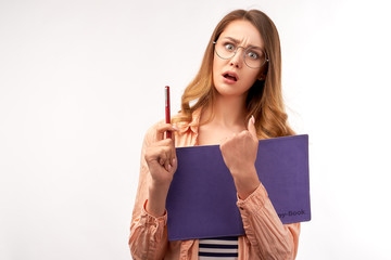 Surprised student woman holds textbook, has scared facial expression, worries before passing entrance exam, wears round spectacles isolated over on white background in Studio