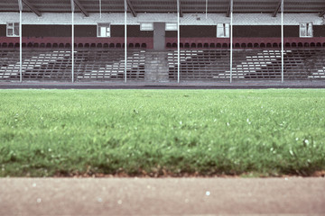Fototapeta premium Empty audience seats at the stadium. In the foreground is a green field in blur.