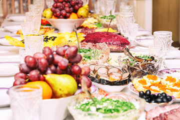 Fototapeta na wymiar Served table. Snacks, fruits, sandwiches, salads, caviar and slicing on the holiday table. Selective focus