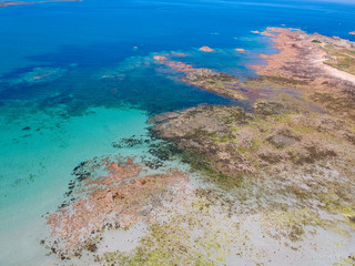Aerial view of wonderful beach with white sand and turquoise water, with some rocks  underwater and few people swimming. Aerial view South coast of Guernsey island, UK, Europe.