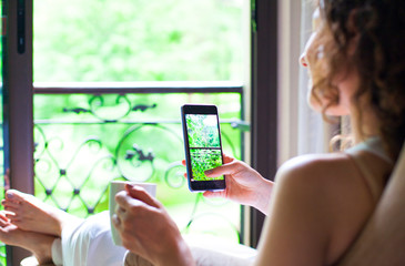 Woman using her smart phone sitting on sofa.