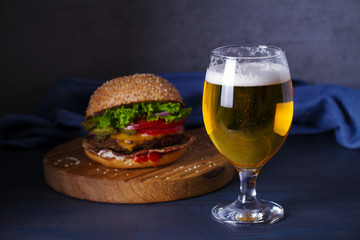 Beer and burger on wooden board for serving. Beer and food concept - Image
