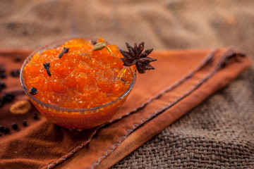 Famous Indian dessert and sweet dish in a glass bowl on jute bag's surface i.e. Murabba or Murba along with entire constituents of it on the surface.Made of Mango.Horizontal shot with only spices.