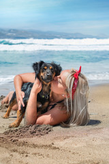 Portrait of a beautiful woman hugging her dog on the beach enjoying the summer day. Vertical. 