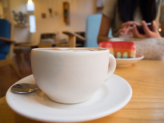 Hot latte art coffee in white cup on wood table