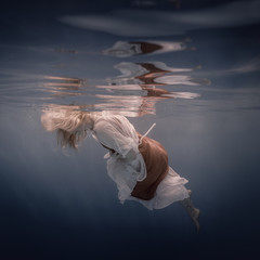 Portrait of a woman in a dress under water.