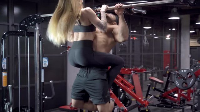 Young sports couple pulling up on the bar together. Crossfit.