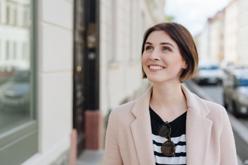 elegante junge frau geht durch die stadt und schaut schaufenster an