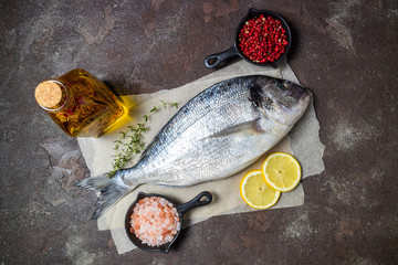 Fresh fish dorado and ingredients for cooking. Raw fish dorado with aromatic spices, herbs, lemon...