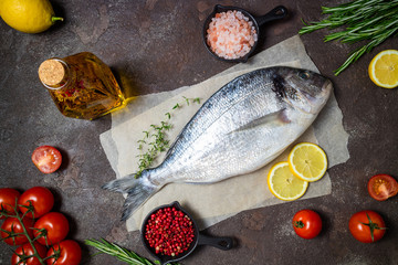 Fresh fish dorado and ingredients for cooking. Raw fish dorado with aromatic spices, herbs, lemon and vegetables. Sea bream fish cooking. Top view