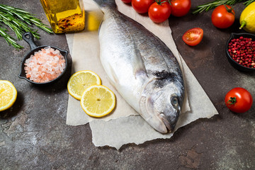 Fresh fish dorado and ingredients for cooking. Raw fish dorado with aromatic spices, herbs, lemon and vegetables. Sea bream fish cooking. Top view