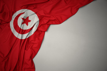 waving national flag of tunisia on a gray background. - obrazy, fototapety, plakaty
