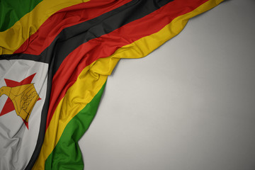 waving national flag of zimbabwe on a gray background.